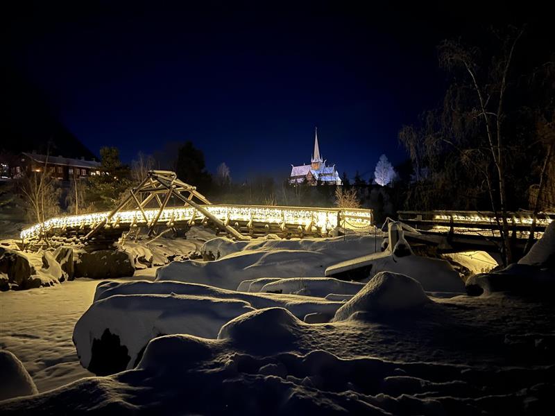 Ljos på Utleggsbrua. Stavkyrkja i bakgrunnen.